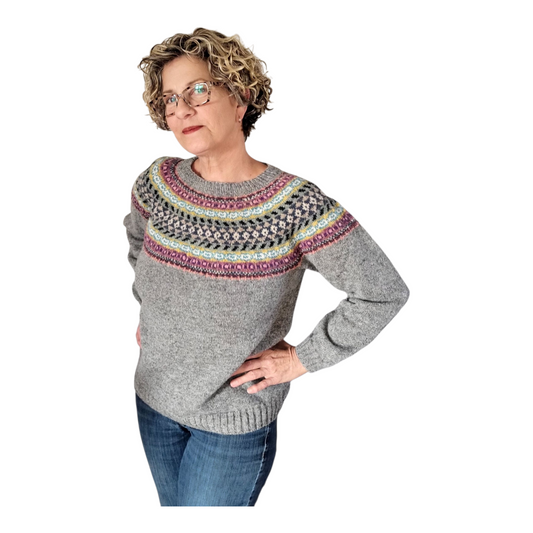 Woman wearing a gray sweater with a colorful pattern on a white background